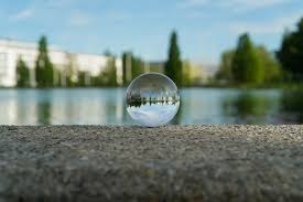 A spherical orb on the side of a lake showing a different perspective on the lake in front of the picture taker