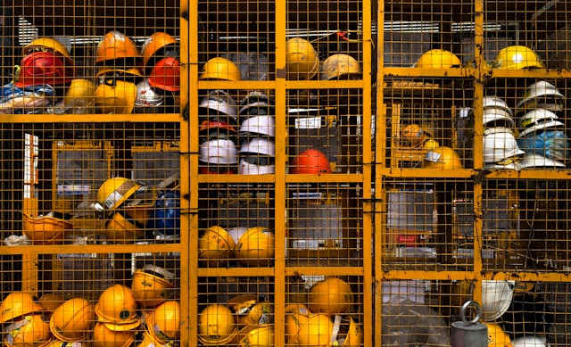 Lockers with cage fronts holding hard hats Photo by Pop & Zebra on Unsplash